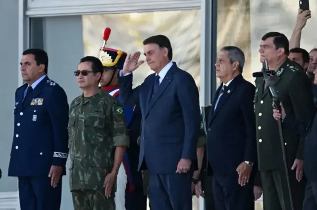 Bolsonaro faz continência durante evento. Ao lado dele há vários militares
